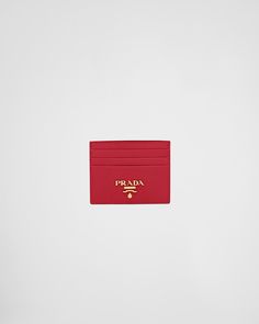 a red prada credit card holder on a white surface with the word prada in gold