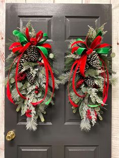 two christmas wreaths hanging on the front door with pine cones and red ribbon around them