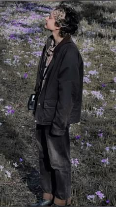 a man standing in the middle of a field with purple flowers