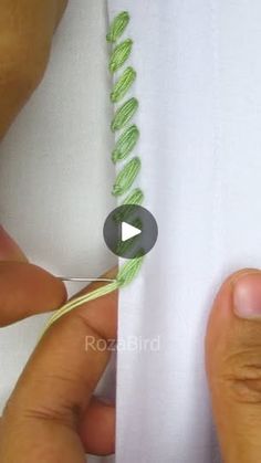 someone is stitching green thread on a white shirt