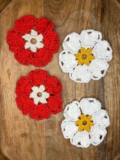 three crocheted flowers sitting on top of a wooden table