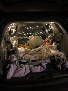 an open car trunk filled with blankets and stuffed animals in the bed area at night