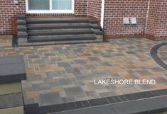 a brick patio with steps leading up to the front door