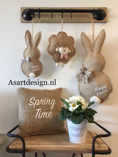 some bunny ears are hanging on the wall above a pillow and vase with flowers in it