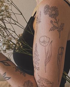 a woman with tattoos on her arm holding flowers