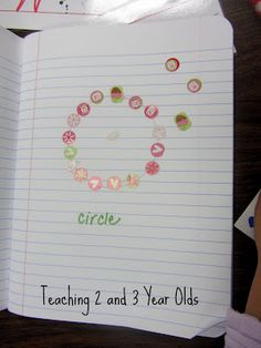 a child's hand holding an open notebook with the words circle written on it