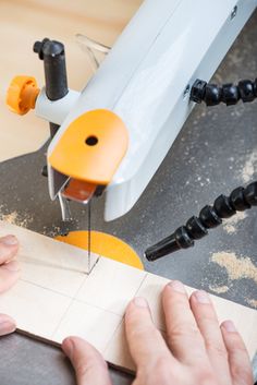 a person is using a machine to cut out some paper on a piece of wood