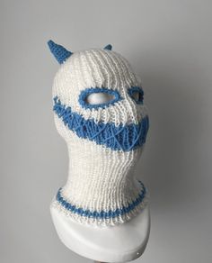 a white and blue knitted mask on a mannequin's head with horns