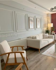 a living room filled with white furniture and wooden flooring next to a large window