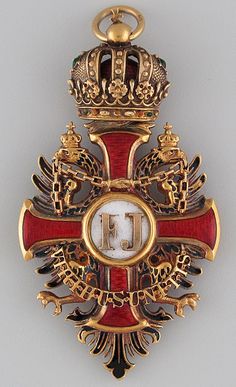 an ornate gold and red cross with a crown on it's back, in front of a gray background