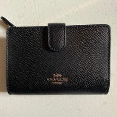 a black coach wallet sitting on top of a table