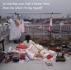 a woman sitting on top of a roof next to lots of clothes and other items