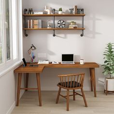 a wooden desk with a laptop on top of it next to a potted plant