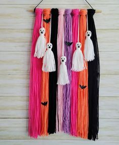 halloween decorations hanging on a wall with long tassels and ghost faces in different colors