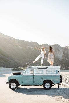 two women are standing on top of a vehicle