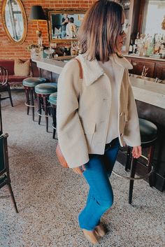 Girl wearing cream boulce coat with jeans and boots in a restaurant. Parisian Capsule Wardrobe, French Outfits, Chic Style Outfits, French Chic Fashion