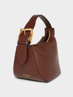 A new addition to the Quiver family, this dynamic-shaped bag is made from Wine smooth-calf leather. It has a simple zip closure and robust handle and features J&M D's statement brass buckle, and comes with a long detachable strap as well. H 14cm, W 22cm, D 16.5cm. Strap drop 55cm Buckle Bag, Clever Gift, Transparent Bag, Fall Denim, Statement Bag, Fancy Bags, Quiver, Bag Collection, Brass Buckle