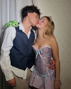 a young man and woman kissing each other in front of a wall with a frog on it