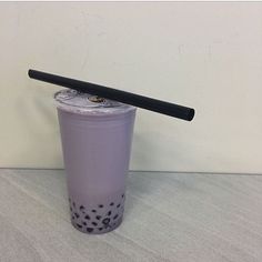 a purple plastic cup with a black handle and polka dot design on the rim, sitting on a table