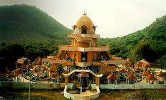 a large building sitting in the middle of a lush green hillside covered with trees and mountains