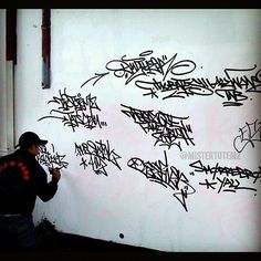 a man writing on a wall with graffiti