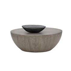 a black bowl sitting on top of a wooden table next to a white wall and floor