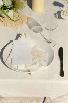 the table is set with white flowers and silverware