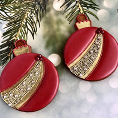 two red and gold ornaments hanging from a christmas tree