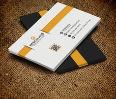 two black and yellow business cards on top of a brown carpeted surface, with the company's logo in the middle