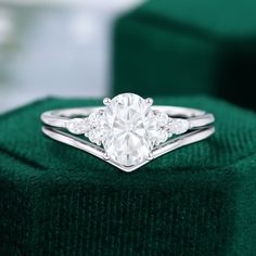 a diamond ring sitting on top of a green velvet cushion