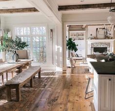 an open kitchen and dining room with wood floors, white walls, and exposed beams