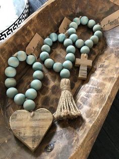 a wooden table topped with blue beads and a tasseled cross on it's side