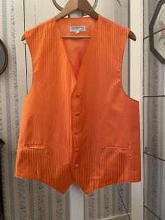 This stunning lightweight vest from Vesuvio Napoli in Italy is true orange with a subtle pinstripe pattern of matte and shiny stripes. The vest has the original matching fabric covered buttons and two front pockets. The back and lining are made of plain orange silky lining. Marked size XL. The measurements, taken with the vest lying flat, are: shoulder to shoulder, 15 inches; armpit to armpit, 22 inches; length, 28 inches in front and 24 inches in back; bottom edge, 24 inches. In very good condition. Casual Fitted Orange Vest, Luxury Red Vest For Workwear, Casual Orange Vest, Orange Waistcoat, Orange Knit Vest, Red Retro Cotton Vest, Vesuvio Napoli, Lightweight Vest, Fabric Covered Button