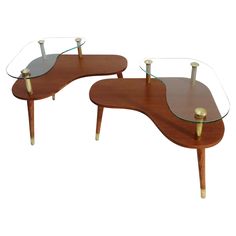 two wooden tables with glass tops and brass legs, one on each side is an oval table