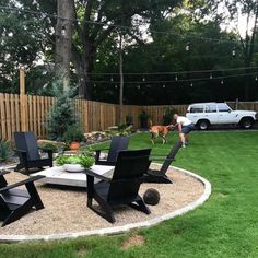 an outdoor patio with chairs and a table in the middle, surrounded by grass near a fence