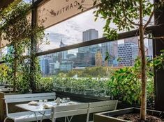 an outdoor dining area with tables, benches and potted plants on the windowsill