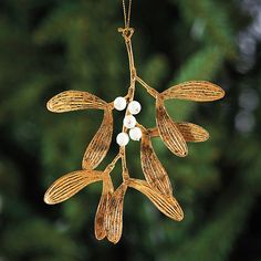 a gold ornament hanging from a tree with white beads on it's branches