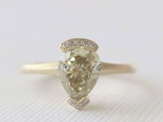 18k yellow gold matte finish half bezel style ring featuring a stunning pear brilliant cut light brownish yellow diamond measuring 8.36 x 6.46 x 5.30 mm and weighing 2.02 carats (VS1 clarity). The center stone is flanked by pave' set round brilliant cut diamonds weighing 0.06 ct (G/VS2,SI1). 2.5 mm tapered band, thins out to 1.8 mm at the bottom. Size 6, can be sized. Original STUDIO 1040 design, certification/appraisal can be requested. *Ready to ship. ** The ring will come with a full gemologi Pear-shaped Yellow Gold Diamond Ring With Rose Cut, Gold Teardrop Diamond Ring For Proposal, Gold Pear-shaped Diamond Proposal Ring, Gold Pear-shaped Diamond Ring For Proposal, Pear-shaped Gold Diamond Ring For Proposal, Gold Pear-shaped Rings With Bezel Setting, Pear-shaped Gold Rings With Bezel Setting, Gold Pear-shaped Diamond Ring With Bezel Setting, Gold Pear Shaped Ring With Rose Cut Diamonds