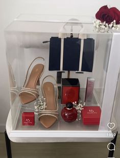 a display case with shoes and accessories on the shelf next to a red rose in a vase