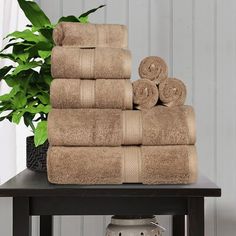 a stack of towels sitting on top of a table next to a potted plant