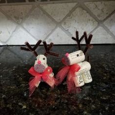 two wine cork reindeers with red bows on them