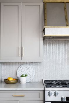 a kitchen with gray cabinets and white counter tops, gold trim on the oven hood