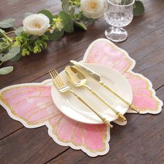 pink and gold butterfly placemats on a wooden table with flowers in the background