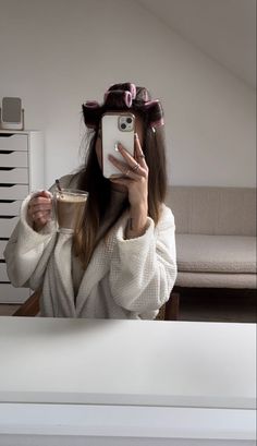 a woman taking a selfie in front of a mirror holding a cup of coffee