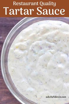 a glass bowl filled with white sauce on top of a wooden table