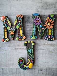 the word mom spelled with colorful painted letters on a wooden surface and decorated with flowers