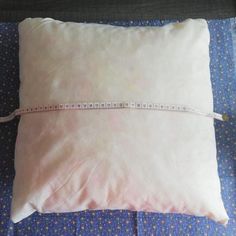 a white pillow with a measuring tape on it sitting on top of a blue bed