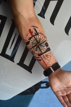 a man's arm with a compass tattoo on his left forearm and the other hand