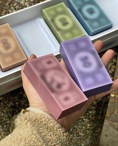 a person holding four different colored boxes in their hand