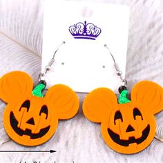 a pair of mickey mouse earring with a pumpkin face on it and a crown in the background